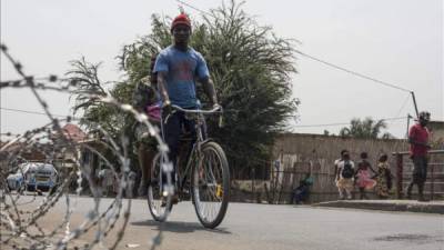 Un ciclista pasa junto a una alambrada de espino en una carrertara de la provincia de Cibitoke, al norte de Buyumbura (Burundi). EFE/Archivo.