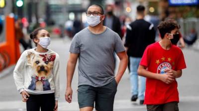 Tres personas con tapabocas caminan por una calle de Sao Paulo.