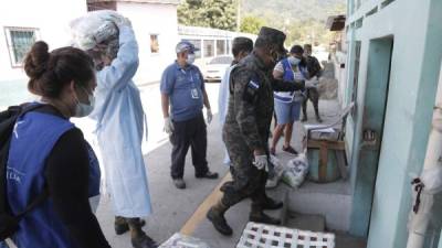 Policías militares y empleados de otras instituciones entregan alimentos casa por casa en la colonia Bordos de Río Blanco, de San Pedro Sula, y las colonias Seden y Misisipi de Choloma. Fotos: Melvin Cubas