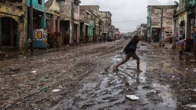 Un hombre atraviesa una enlodada calle de Puerto Príncipe, la capital haitiana. El país caribeño fue muy golpeada por fenómeno climático.