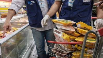 Inspectores de la agencia brasileña de protección al consumidor retiran empaques de productos avícolas en un supermercado de Río de Janeiro.