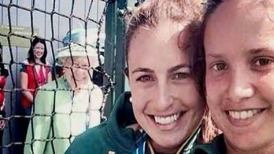 La reina Isabel II se observa al fondo de esta selfie que se toman dos jugadoras.