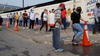 AME4805. TEGUCIGALPA (HONDURAS), 22/04/2020.- Un trabajador desinfecta este miércoles el calzado de ciudadanos que entran a un mercado callejero, en Tegucigalpa (Honduras). El pico de contagios por COVID-19 en Honduras llegará probablemente a principios de junio, aseguró este miércoles la Organización Panamericana de la Salud (OPS), que señaló además que el distanciamiento social es la mejor forma de prevenir la enfermedad. 'Establecer el pico de contagio es muy difícil, pero según la mayoría de los cálculos se está hablando de principios o mediados de junio', dijo la representante de la OPS en Honduras, Piedad Huerta, en una entrevista con Efe. EFE/Gustavo Amador