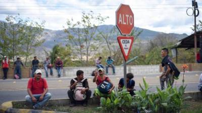 Migrantes hondureños a la esperan en una carretera por un medio de transporte en Zacapa, Guatemala.