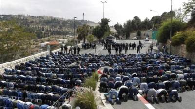 Policías fronterizos hacen guardia frente a un grupo de palestinos durante los rezos del viernes hoy en Jerusalén. EFE