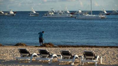 Un solitario trabajador limpia un trecho de playa en Punta Cana, uno de los principales polos turísticos del país caribeño.