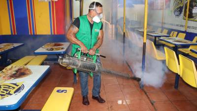 Empleado de la Municipalidad de San Pedro Sula fumiga un comedor de mercado.
