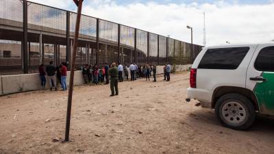 Un grupo de 22 migrantes de Honduras, Guatemala y Salvador detenidos para su procesamiento debajo del Puente Paso Del Norte esperan ser transportados el 28 de marzo de 2019 en El Paso, Texas.
