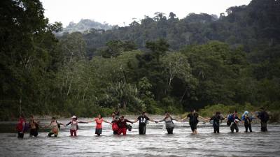 Migrantes cruzanndo el río Turquesa en Darién (Panamá).