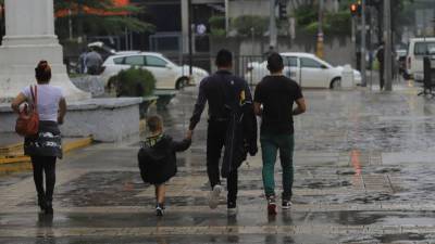 Personas caminan bajo la lluvia en Honduras | Fotografía de archivo