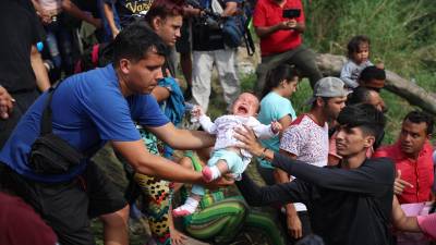 Un grupo de migrantes se prepara para cruzar el Río Grande con un bebé en brazos a pocas horas de que se suspenda el Título 42.