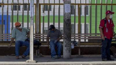 Hombres con tapabocas esperan en una parada de autobús, este viernes en Managua. Foto: EFE