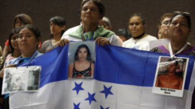 Members of a caravan of Central American mothers, holding a Honduran flag and photographs of their disappeared children, attend a mass at the Basilica of Guadalupe in Mexico City, Sunday, Oct. 28, 2012. The convoy, mostly comprised of women from Central America, travels through Mexico to search for their relatives who left for a better life and then disappeared on their journey to the U.S. About 100 have been reunited through similar trips through Mexico over six years. (AP Photo/Marco Ugarte)
