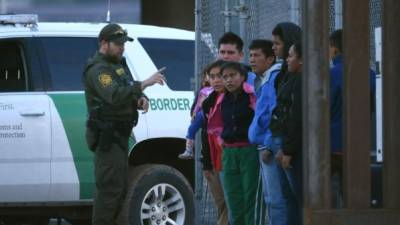 Un agente migratorio estadounidense intercepta a un hombre junto a su esposa e hijas tras ingresar a territorio norteamericano por la valla fronteriza que separa México de Estados Unidos. EFE