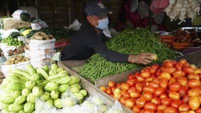 Un vendedor con mascarilla del mercado Dandy acomoda las verduras en su negocio. Foto: Amílcar Izaguirre.