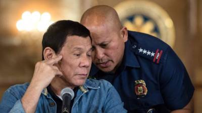 El director nacional de la policía filipina, Ronald Dela Rosa, susurra al oído del presidente Rodrigo Duterte.