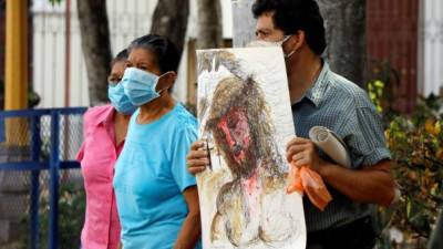 Fieles salen a la calle mientras pasan carros con una procesión este Viernes Santo en una parroquia de Tegucigalpa. Foto EFE