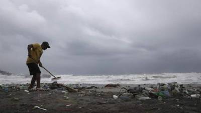 Un hombre limpia la playa de Haina, donde se registra un fuerte oleaje por efecto del paso del huracán Matthew, ayer en Haina, República Dominicana. EFE