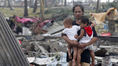 Un padre filipino y sus hijos esperan ayuda alimentaria fuera de su tienda de campaña en el súper tifón Yolanda que devastó la ciudad de Tacloban, provincia de Leyte, DENNIS M. SABANGAN (EFE)