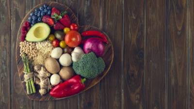 Healthy food on a heart shape cutting board. Love of food concept with fruit, vegetables, grains and high fibre foods. Rustic wood textures