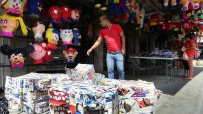En el mercado Medina, un vendedor de piñatas, hechas de periódico, muestra la variedad con la que cuenta en su tienda.