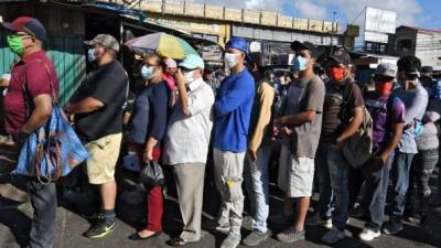 People queue at the crowded El Mayoreo market in Tegucigalpa on March 23, 2020 despite an 'absolute curfew' ordered by the Honduran government to slow the spread of the new coronavirus, COVID-19. - Days ago, the government decreed 'an absolute curfew' to force the population to isolate themselves in their homes and curb the spread of the virus in the poor Central American country (Photo by Orlando SIERRA / AFP)