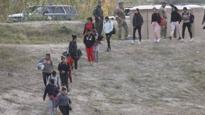 Los migrantes caminan cuesta abajo en Shelby Park en Eagle Pass Texas.