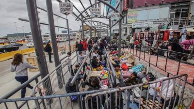 Migrantes de diferentes nacionalidades, descansan en la entrada de la garita peatonal de San Ysidro, hoy para solicitar asilo a las autoridades estadounidenses, en Tijuana (México).
