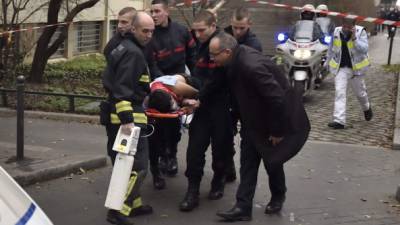 Una víctima es trasladada en camilla después de hombres armados irrumpieron en las oficinas del periódico satírico francés Charlie Hebdo en París, dejando al menos 11 muertos. AFP