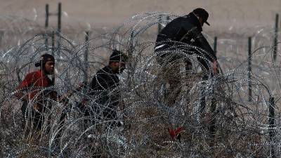 Migrantes intentan cruzar la cerca de alambres en la frontera que divide a México de los Estados Unidos, el 23 de febrero de 2024, en Ciudad Juárez (México).