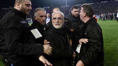 El presidente y propietario del PAOK griego, Ivan Savvidis (centro), abandona el terreno de juego escoltado por sus guardaespaldas, tras invadir el campo con una pistola. FOTO EFE.