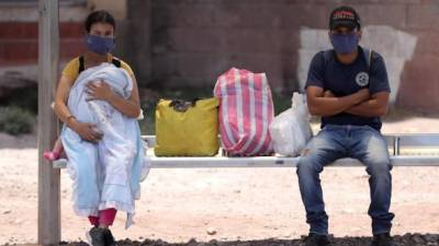 Dos personas esperan en un paradero de autobuses, este lunes, en Tegucigalpa (Honduras). Fotos: EFE