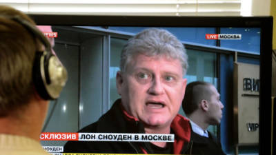 A man looks in Moscow on October 10, 2013, at a computer screen displaying Lon Snowden (R), the father of US intelligence leaker Edward Snowden, speaking during his interview with Russian website LifeNews upon his arrival in at Moscow's Sheremetyevo airport. Lon Snowden arrived early today in Moscow, hoping to meet his son for the first time since the latter became a fugitive. AFP PHOTO