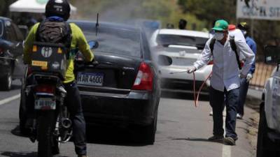 Autoridades hondureñas desinfectan vehículos que entran al municipio de Santa Lucia, el pasado lunes, al noreste de Tegucigalpa (Honduras). EFE/Gustavo Amador