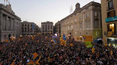 Catalanes celebran la declaración de independencia ante el Palau de la Generalitat. Agentes de los Mossos d´esquadra en Cataluya Radio, atacada por opositores. / AFP PHOTO / LLUIS GENE