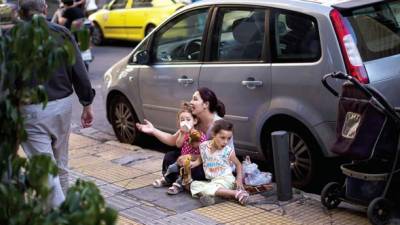 Una mujer y sus dos hijos piden limosna en el centro de Atenas.
