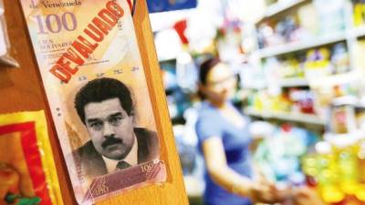 Un ‘devaluado’ billete de 100 bolívares con la cara del presidente Nicolás Maduro adorna un supermercado en Caracas.