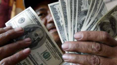 A woman counts money outside a U.S. remittance collection agency in San Isidro, 70 km northeast of San Salvador, on June 10, 2020, amid the new coronavirus pandemic. - The drop of remittances, which represents the 16% of the gross domestic product (GDP) of El Salvador, is attributed to the loss of jobs in the US due to the COVID-19 pandemic. GUatemala and Honduras have also seen their incomes reduced. (Photo by MARVIN RECINOS / AFP)