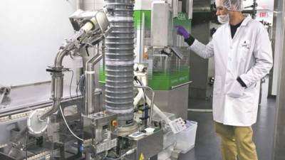 Un operador de un laboratorio farmacéutico trabajando en una máquina de producción de medicinas. Foto archivo.