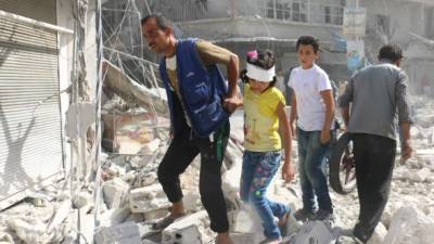 Un grupo de habitantes de un barrio de la zona rebelde de Alepo caminan entre los escombros dejados por los ataques. Foto: AFP/Ameer Alhalbi