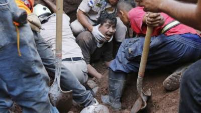 En medio de lamentos, los bomberos rescataron con vida al joven Rafael Antonio Silva, quien estuvo soterrado bajo un alud de tierra.