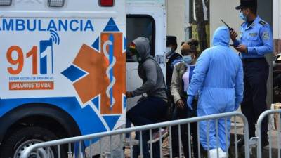 Hondurans who entered the country in the last hours are escorted by authorities as they enter an ambulance to be put in quarantine at the Jose Simon Azcona sports complex to prevent the spread of the new coronavirus in Tegucigalpa on March 18, 2020. (Photo by ORLANDO SIERRA / AFP)