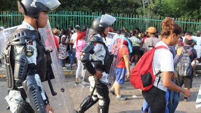 Policías vigilan a migrantes que hacen fila para conseguir documentación para transitar por el país en la ciudad de Tapachula en Chiapas (México).