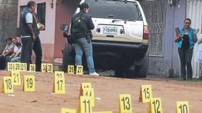 Técnicos de la DNIC hacen la requisa en la escena del crimen en la calle principal de la colonia Las Palmas de Tegucigalpa.