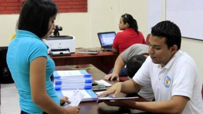 Encargado de la recepción de documentos entrega la guía a una aspirante.