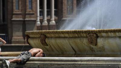Un joven se refresca en una fuente en medio de una ola de calor en España.