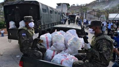 Camiones militares llegaron hasta la colonia Los Pinos en la capital y en calles escabrosas y subiendo cuestas entregaron las bolsas con comida a cada familia(Photo by Orlando SIERRA / AFP)