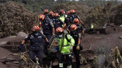 TOPSHOT - Municipal firefighters carry the body of a victim of the Fuego Volcano eruption recovered during a search in the ash-covered village of San Miguel Los Lotes, in Escuintla Department, about 35 km southwest of Guatemala City, on June 6, 2018.Nearly 200 people are missing and at least 75 have been killed since Guatemala's Fuego volcano began erupting over the weekend, officials said Tuesday. / AFP PHOTO / Johan ORDONEZ