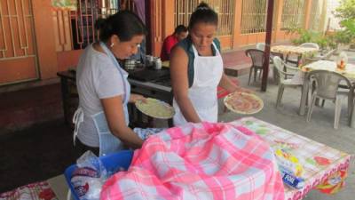 Dos mujeres jóvenes sirven comida en un merendero en Nacaome, Valle.