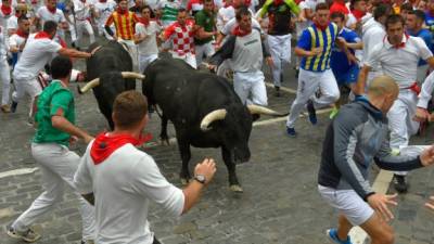 Participants run next to Puerto de San Lorenzo fighting bulls during the first bullrun of the San Fermin festival in Pamplona, northern Spain on July 7, 2019. - On each day of the festival six bulls are released at 8:00 a.m. (0600 GMT) to run from their corral through the narrow, cobbled streets of the old town over an 850-meter (yard) course. Ahead of them are the runners, who try to stay close to the bulls without falling over or being gored. (Photo by ANDER GILLENEA / AFP)